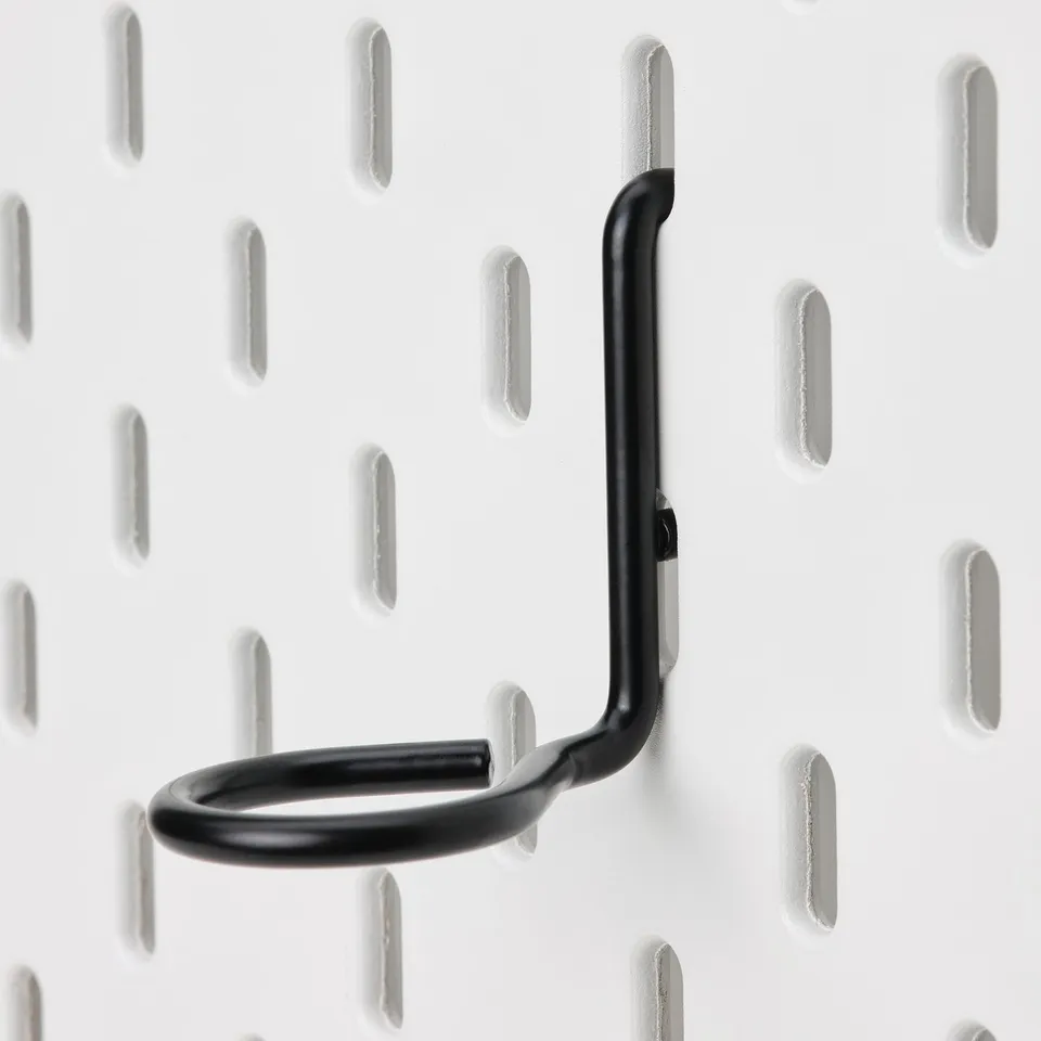 Black metal hook securely attached to white pegboard, showcasing sturdy design and quality.