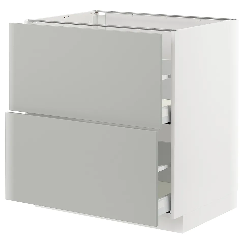 Depicts a white METOD cabinet with light grey drawers featuring a modern, clean design.