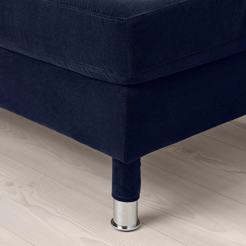 Modern sofa corner with deep blue velvet upholstery and chrome legs.