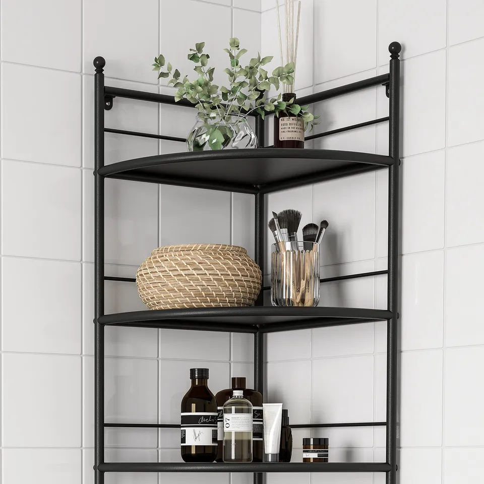 Black metal corner shelf holds basket, makeup brushes, toiletries, and vase with greenery.