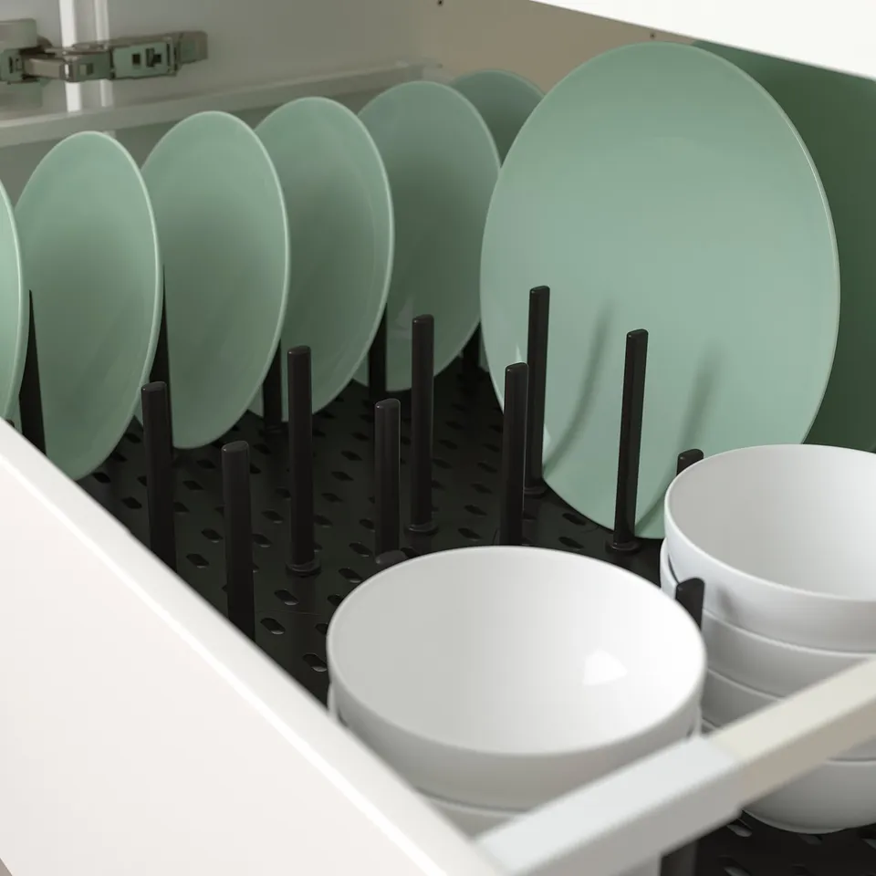 Kitchen drawer organiser with adjustable pegs keeps plates and bowls in place. Black pegs hold mint green and white dishes neatly.