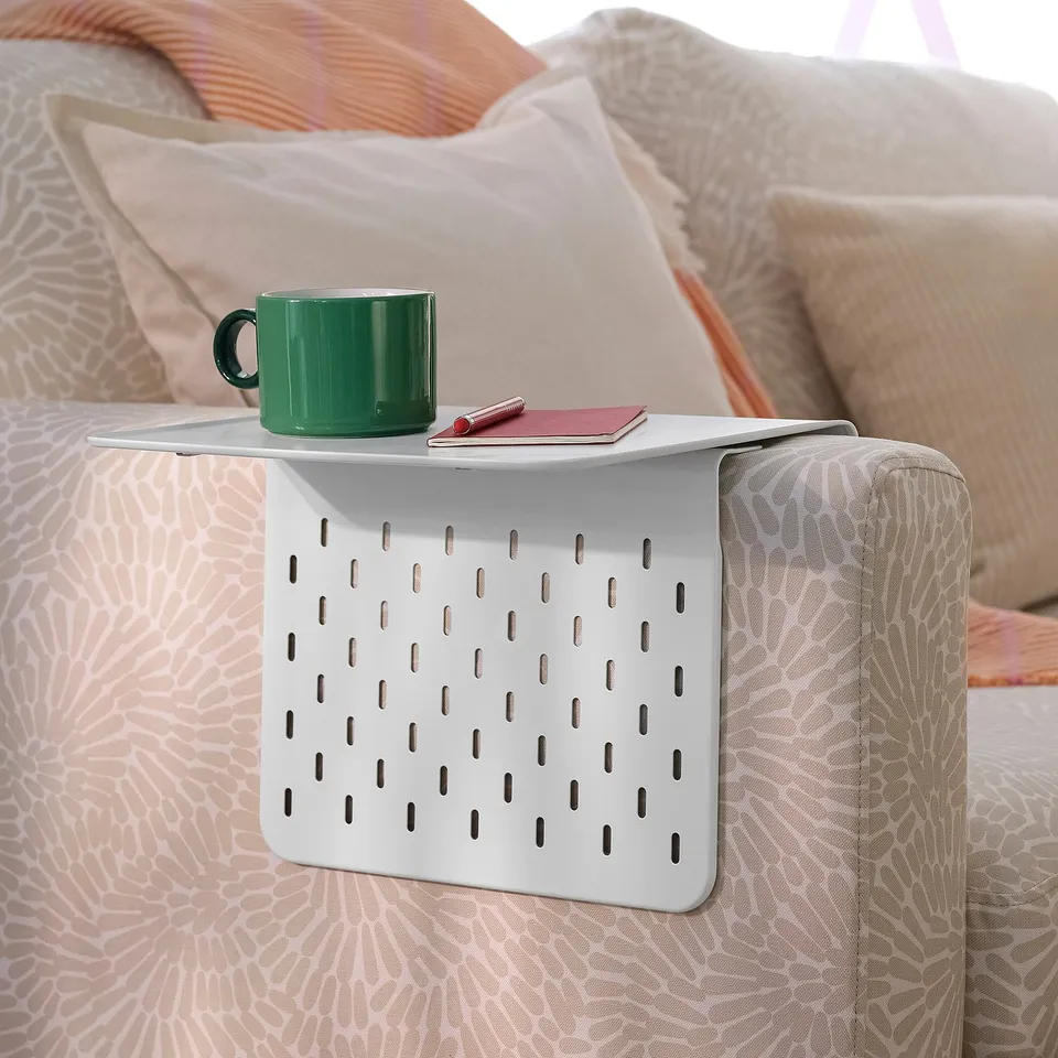 Green mug on adjustable white armrest tray.