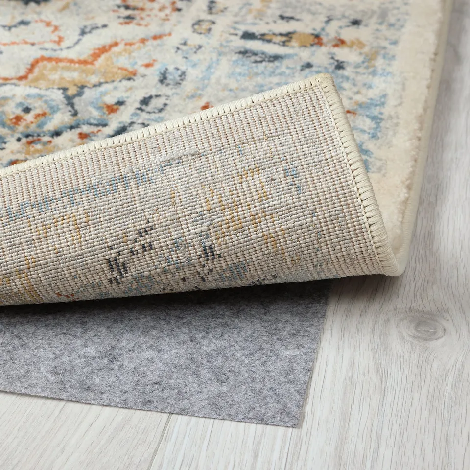 Image shows a stylish rug with intricate patterns, likely hand-tufted with high-quality materials, lying on a light wooden floor.