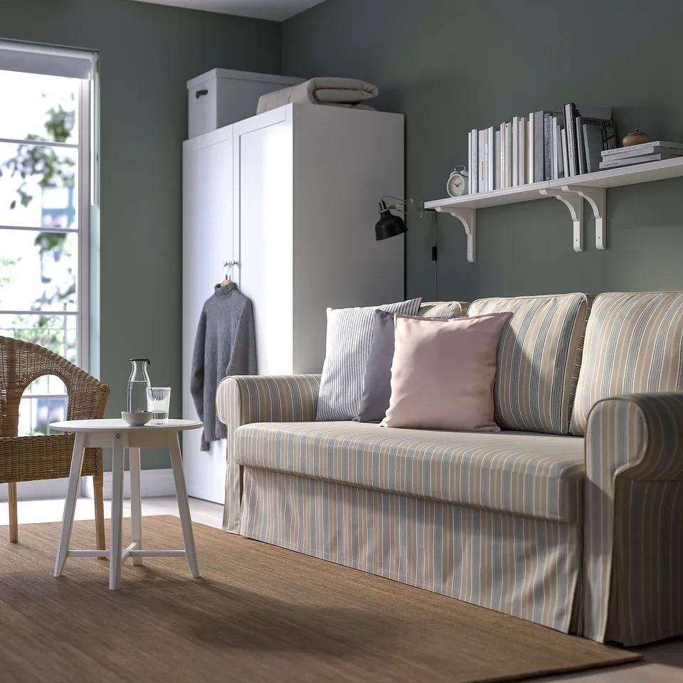 Modern living room with VRETSTORP sofa-bed, white cabinet, and bookshelf. Sofa has striped grey and white cover.
