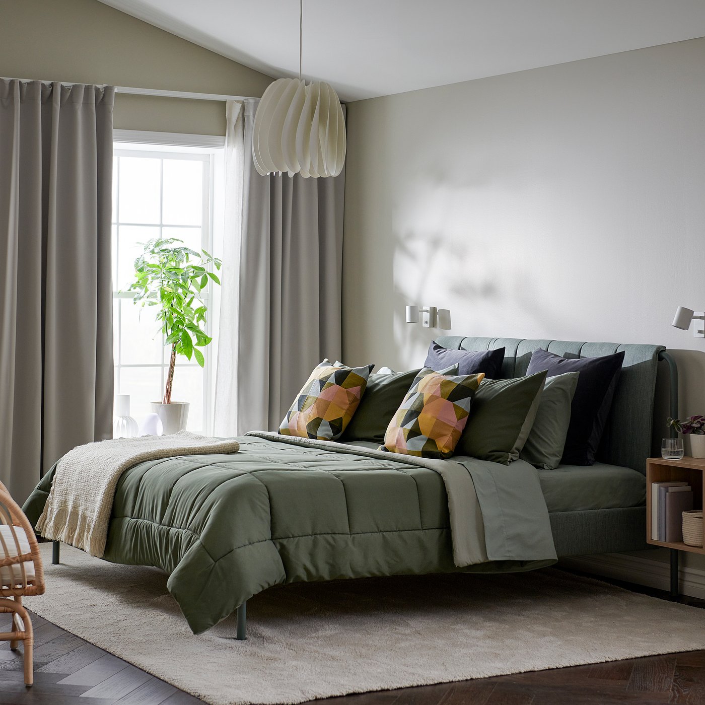 Modern bedroom with large HEDFRYLE green comforter set on bed, geometric pillows, grey curtains, hanging plant, and stylish lighting.