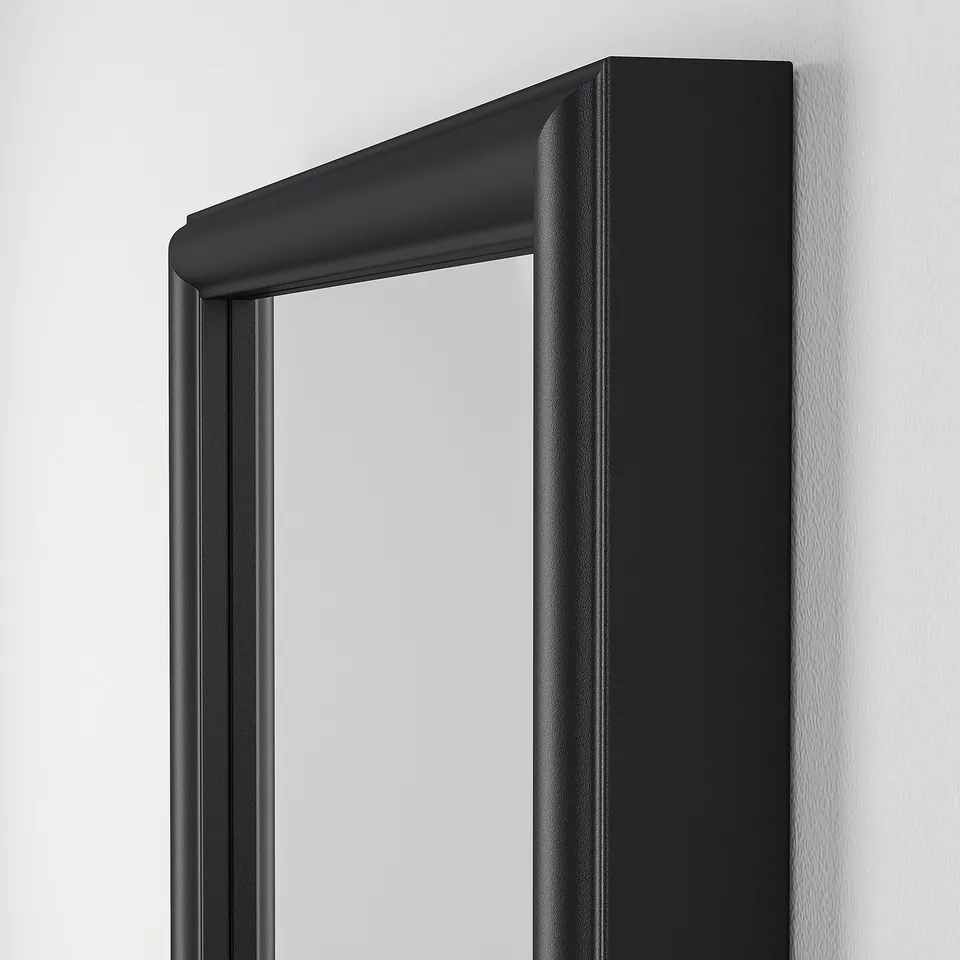 Black-framed mirror with sleek design, reflected grey wall.