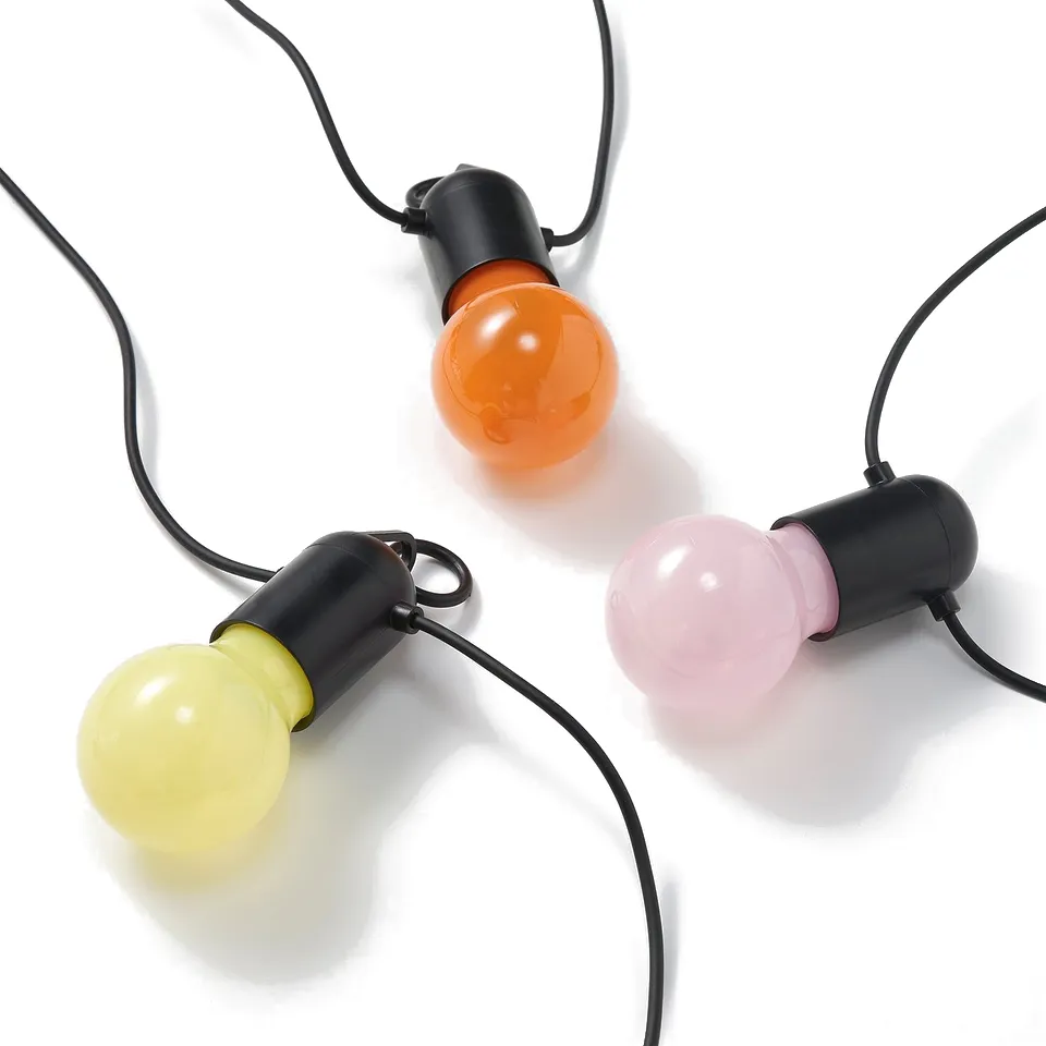Yellow, orange, pink bulb string lights on black cords, white background.