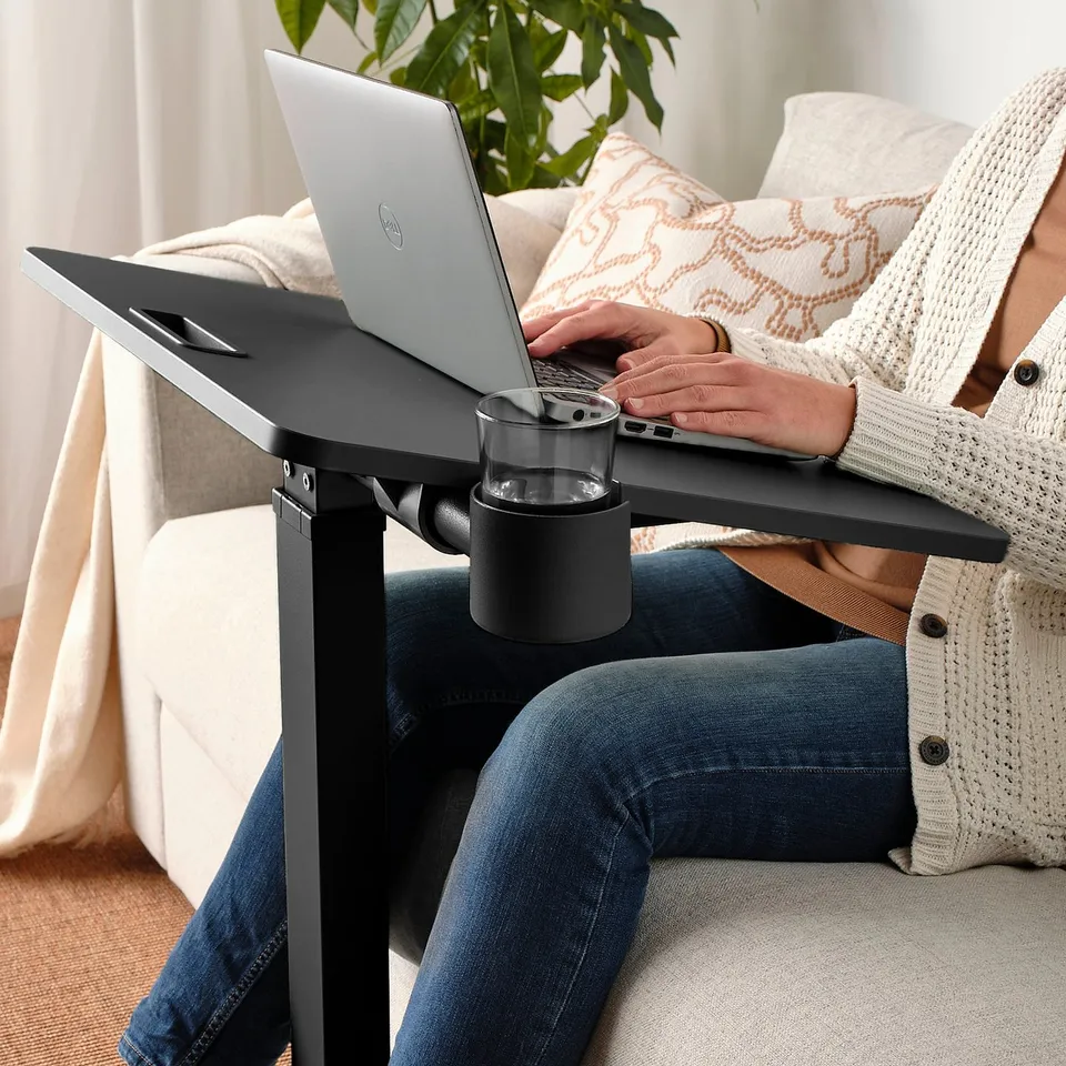 Person using height-adjustable laptop table on couch, typing on laptop.