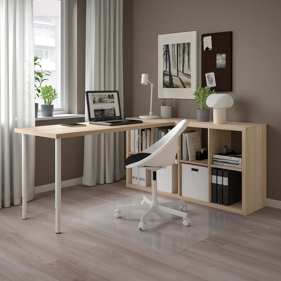 Modern office setup with light-colored KALLAX shelves, computer, chair, books, and decorations.