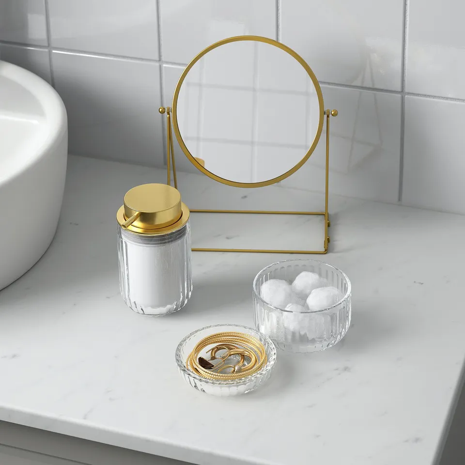 Marble counter with magnifying mirror, cotton jar, bracelets, and cotton bowl.