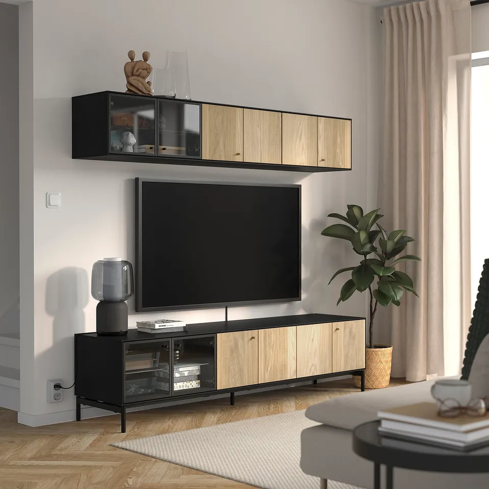 Modern living room with black & oak tv bench, flat screen tv, and wall shelf with lighting and decor.