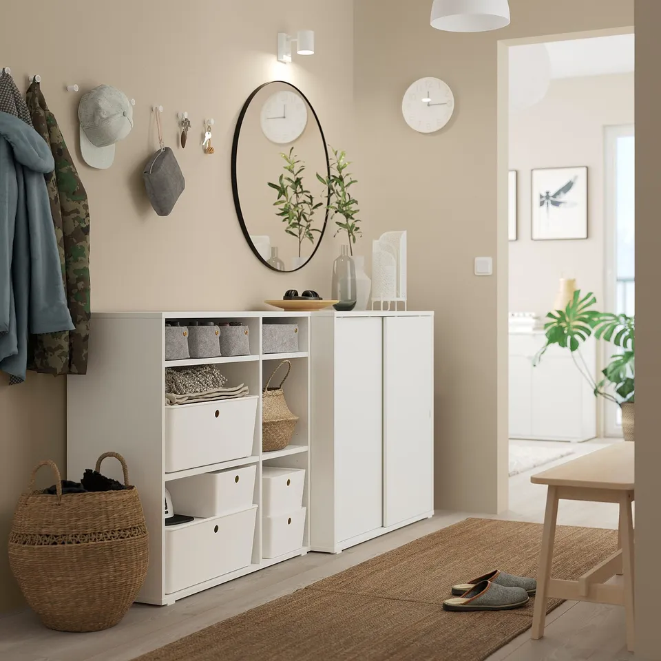 Modern entryway with white VIHALS storage units, mirror, and hangers. Neatly organised with beige decor and accessories.