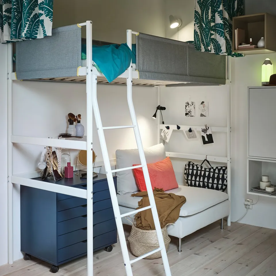 Bedroom with VITVAL white bunk bed, blue comforter, ladder, drawers, shelves, couch, pillows, walls with leaf design.