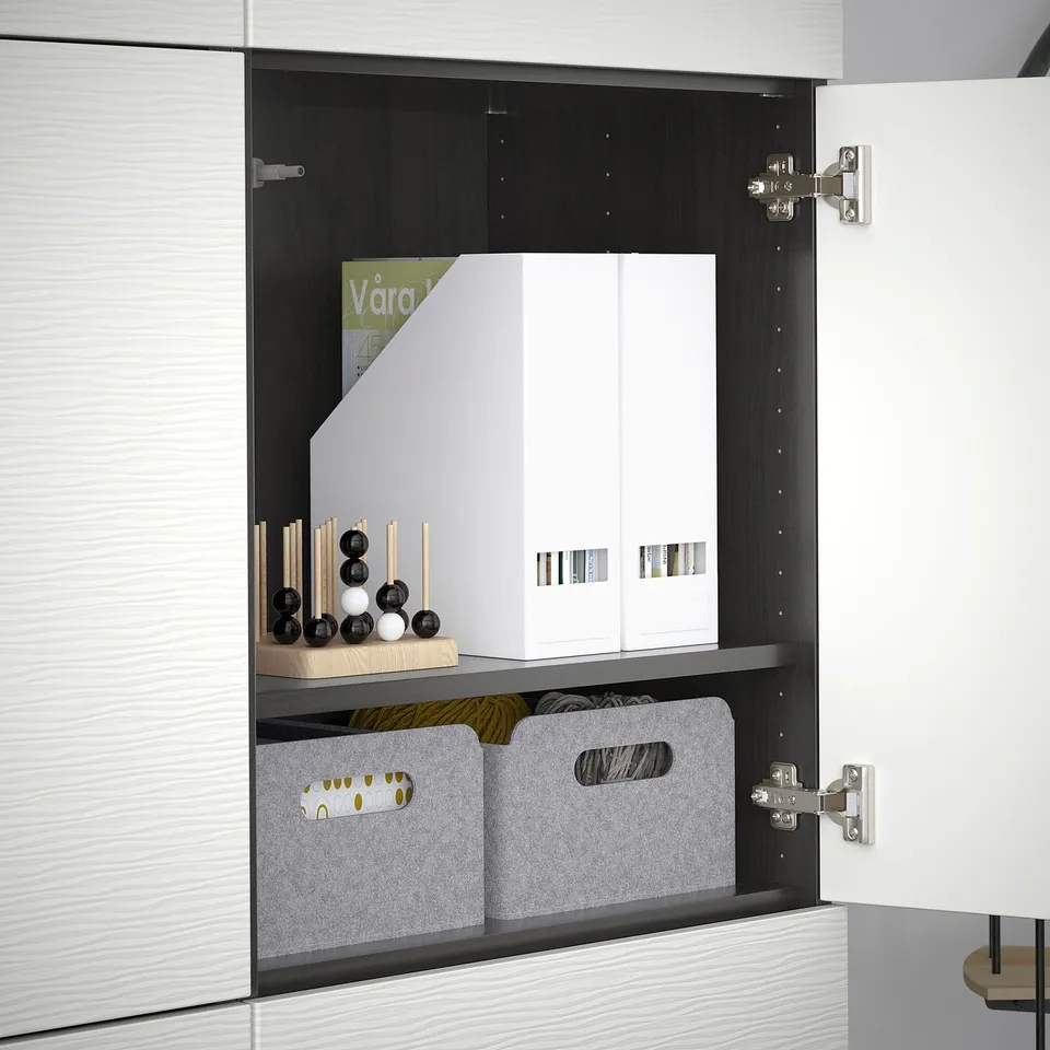 Open BESTÅ cabinet with adjustable shelves and hinges. White organiser, grey bins, wooden and black decor on shelves.