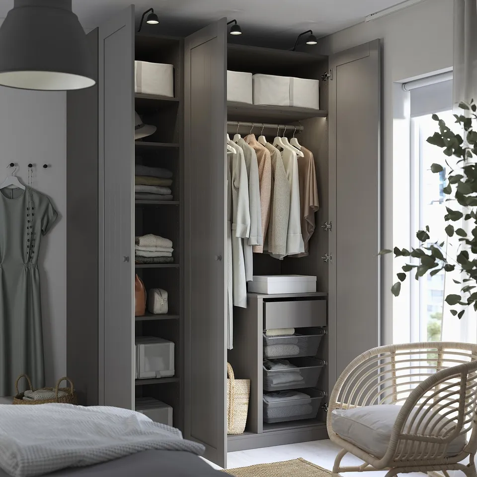 Modern bedroom with open PAX wardrobe and wicker chair.