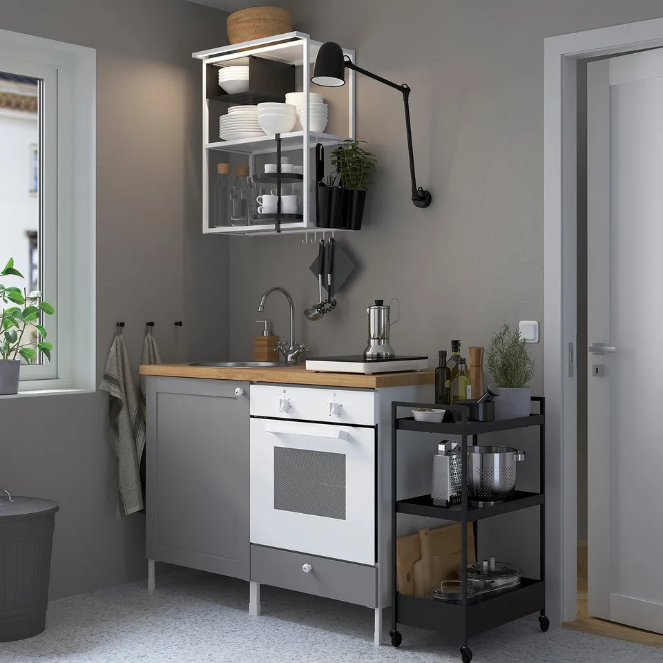 Compact modern kitchen with grey SKYDRAG light above cabinet, white oven, wooden counter, and black trolley.