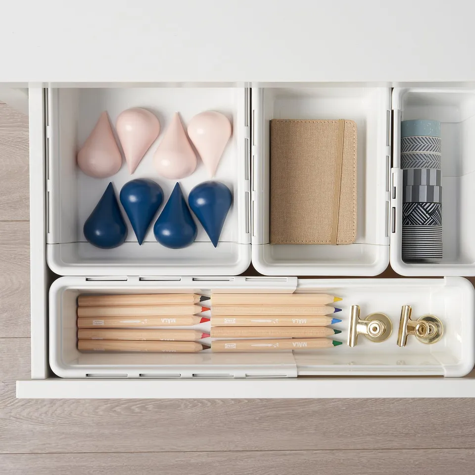 Organised drawer with KACKLA extendable boxes. Includes coloured pencils, rubber toys, fabric, and ribbon organised in compartments.