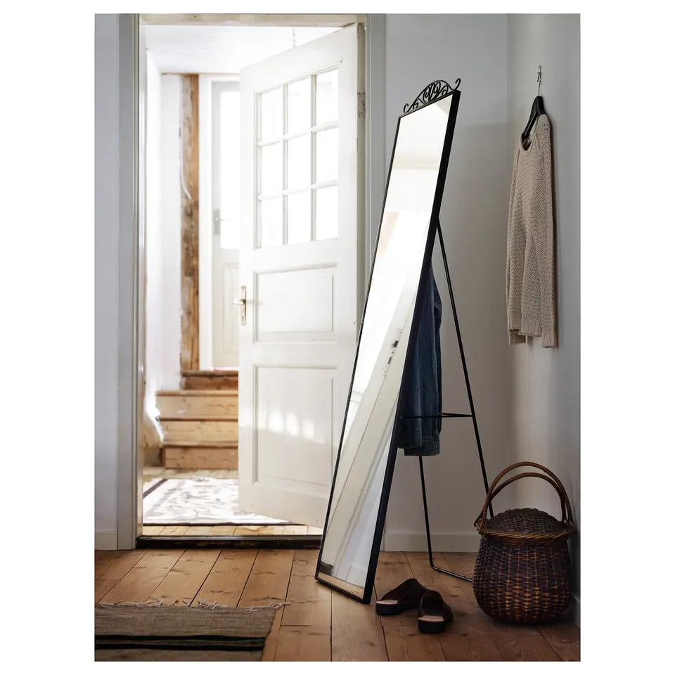 Black KARMSUND mirror in hallway with hooks, basket, slippers.