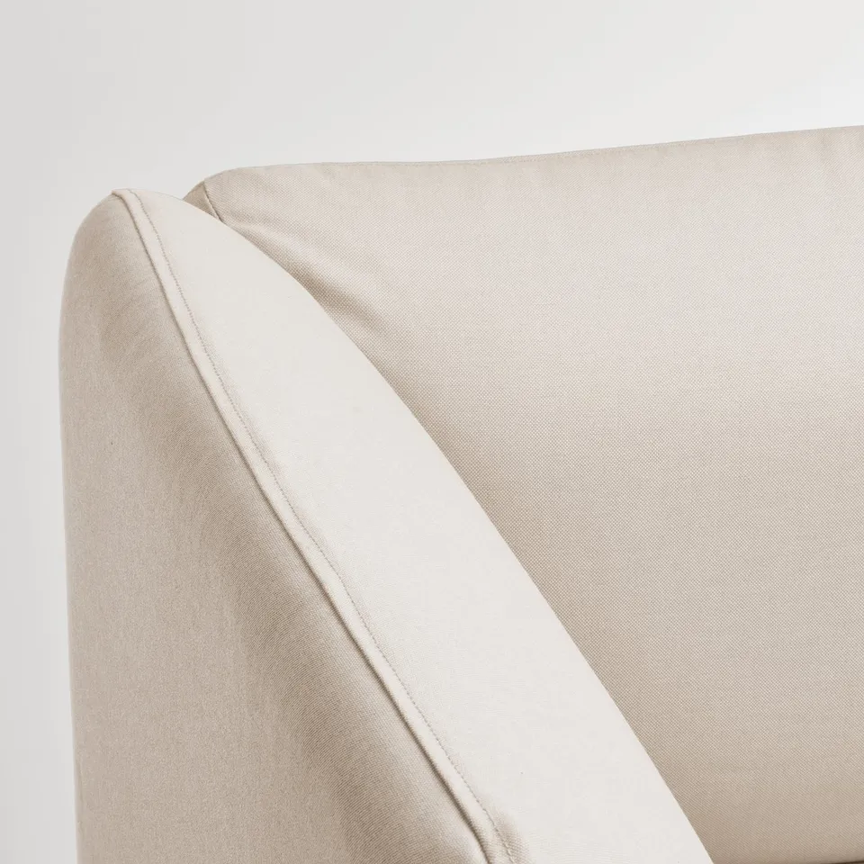 Sofa corner detail: smooth, beige fabric with clean stitching.