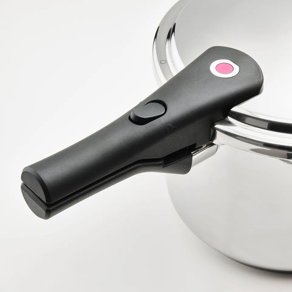 Black plastic handle with red button on stainless steel pressure cooker.