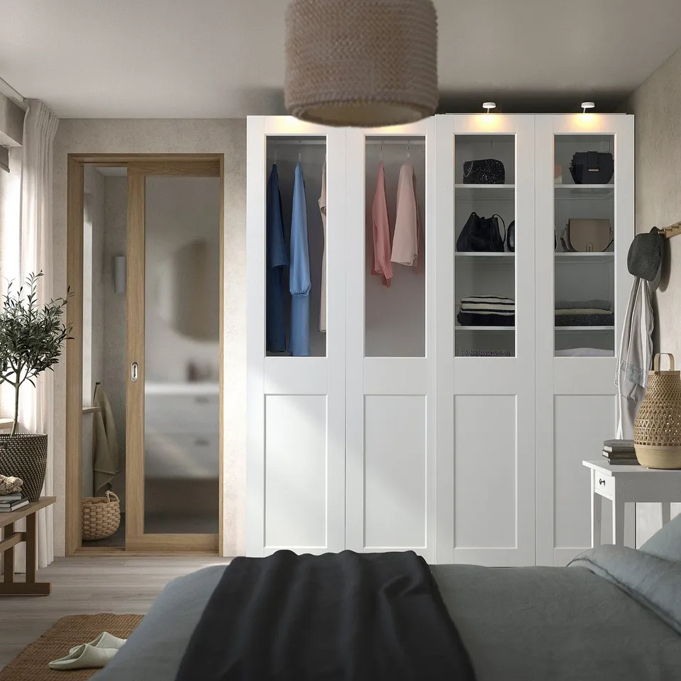 Modern white wardrobe with glass panels and purses. Tall, sleek with textured lampshade.