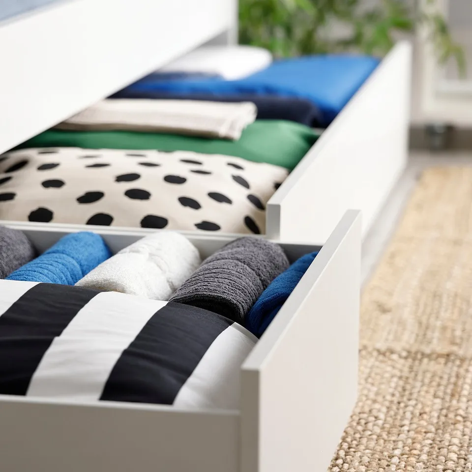 Open drawer unit with folded blankets and towels, showcasing organised storage.