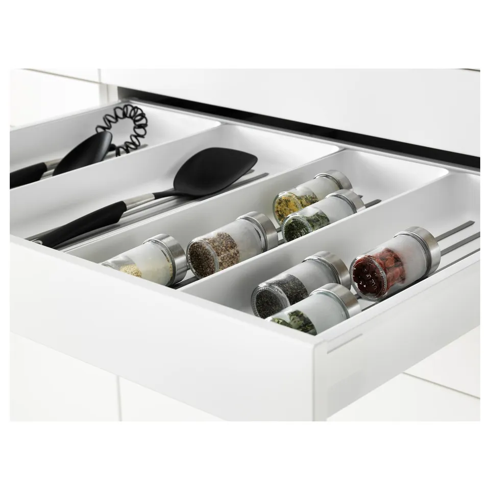 White kitchen drawer organiser with spice jars and utensils, part of METOD system.