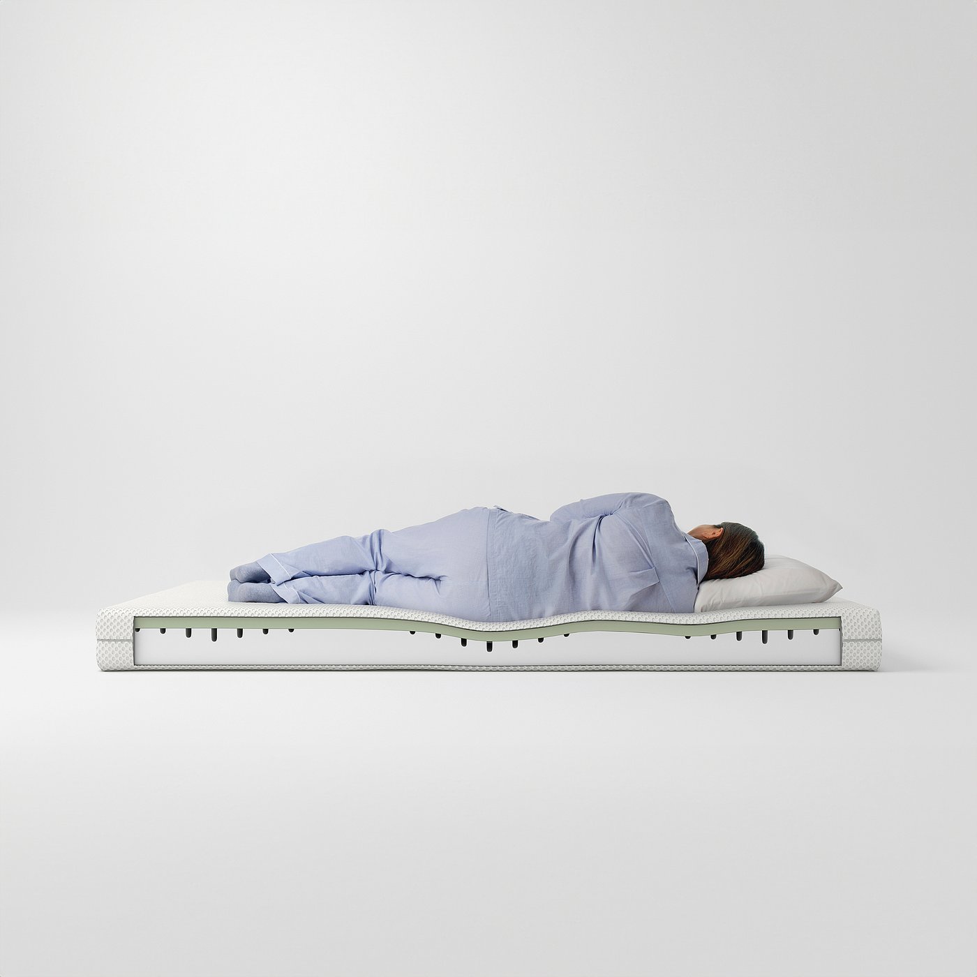A person sleeping on a blue ÅBYGDA mattress, which is white with green accents and has a layered foam design.