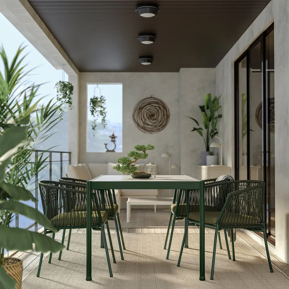 Modern outdoor dining set with green metal table and chairs on a balcony, surrounded by plants.