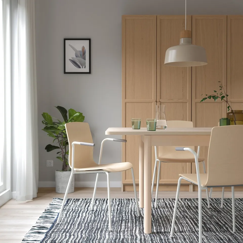 Modern dining room with wooden table, LÄKTARE chairs, pendant light, rug, plant, and art.