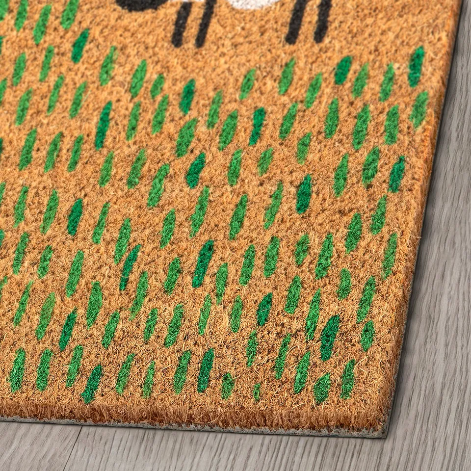 Natural coir door mat with green pattern, durable and eco-friendly, laid on wooden floor.