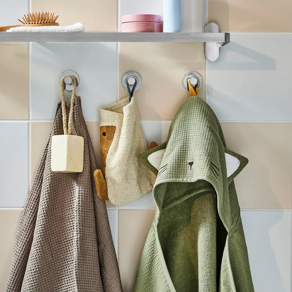 Three towels hang: grey, beige, green. Alternatively, for a bit more detail: hanging towels: grey with soap, beige with duck, green with cat ears.