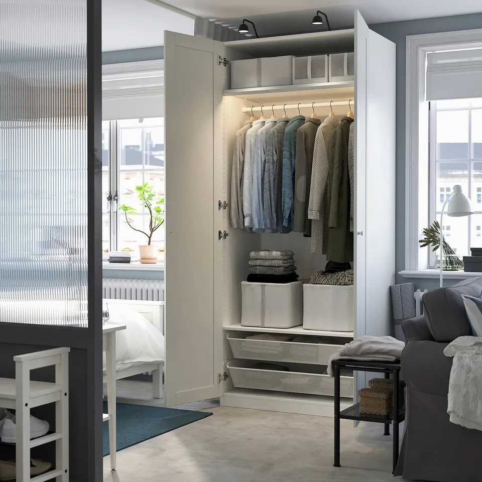 Open wardrobe displaying clothes, folded items, and storage boxes inside a bright, organised room.