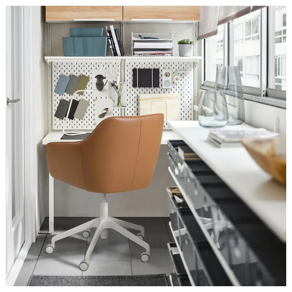 Modern home office: orange leather swivel chair, pegboard, books, plants on desk.