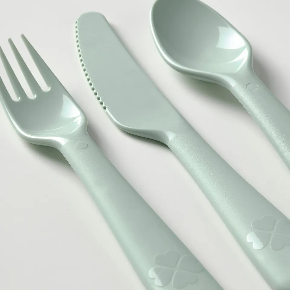 Mint green kids cutlery: fork, knife, spoon on white surface.