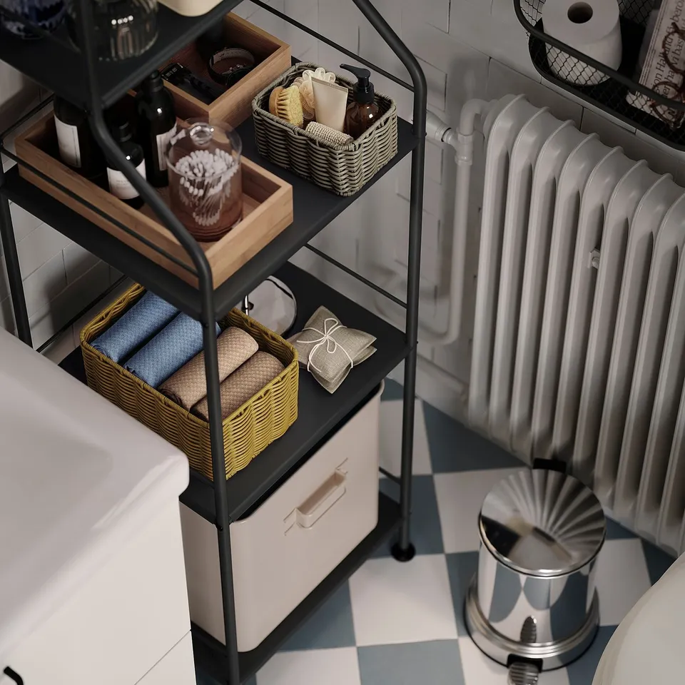 Metal bathroom shelves with baskets of towels and toiletries, between sink and radiator.