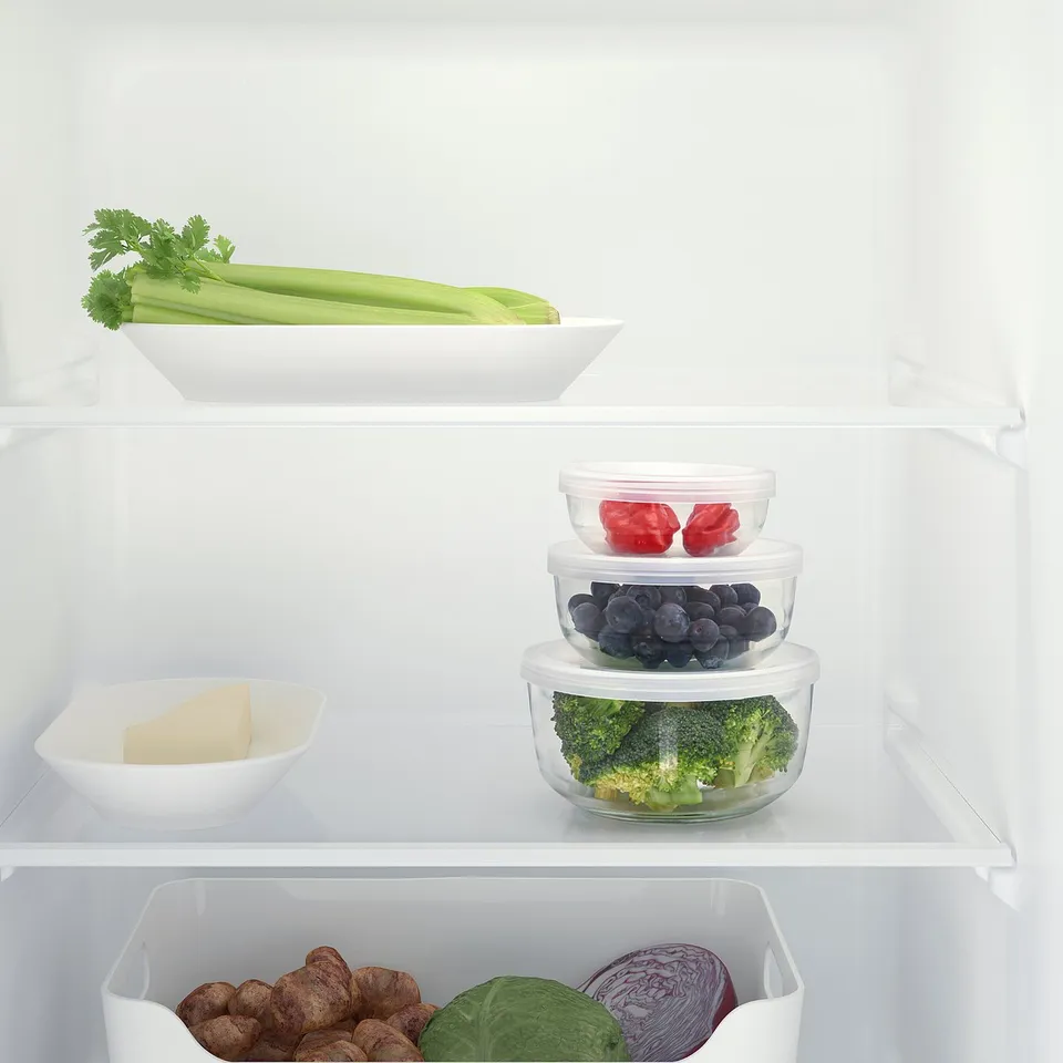 Fridge shelf with glass containers holding fruits, veggies, and cheese. Stackable, transparent, and odor-resistant for easy access and storage.