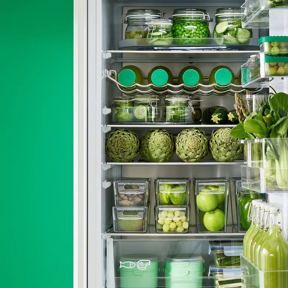 Fridge with organised produce: clear boxes stacked, labelled, showing various fruits and veggies.