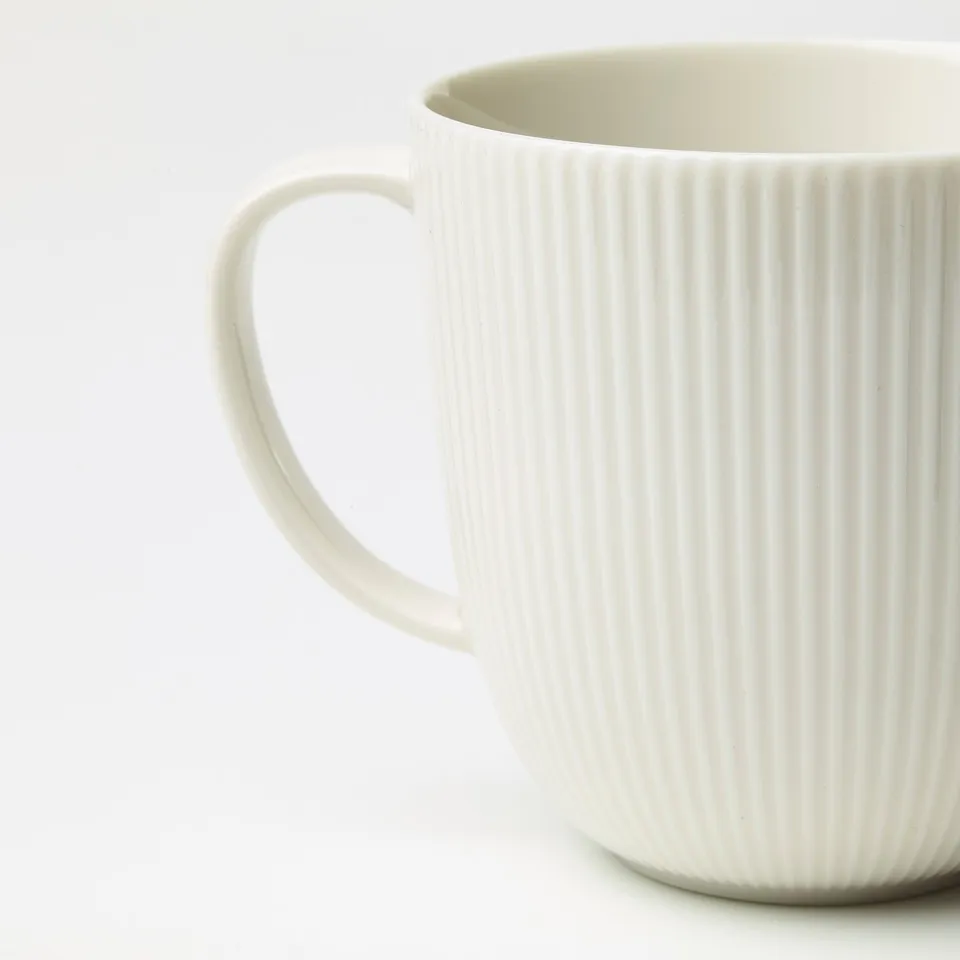 Elegant white mug, ribbed texture, smooth handle. Crafted from durable porcelain.