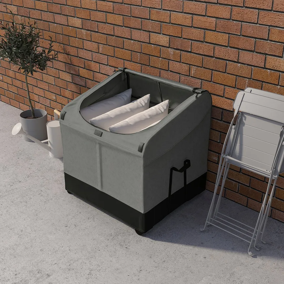Grey VÄTTERSÖ box with cushions, plant, and chair against wall.