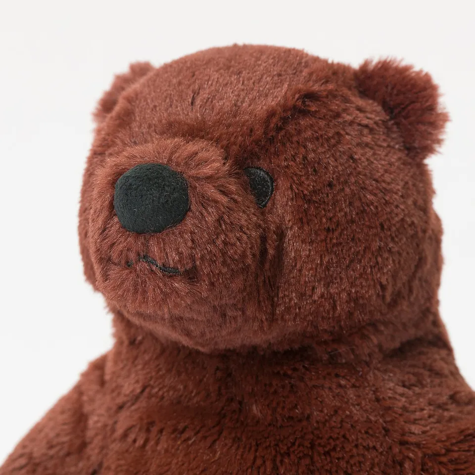 Brown teddy bear close-up; soft, plush fur; dark green safety eyes and nose.