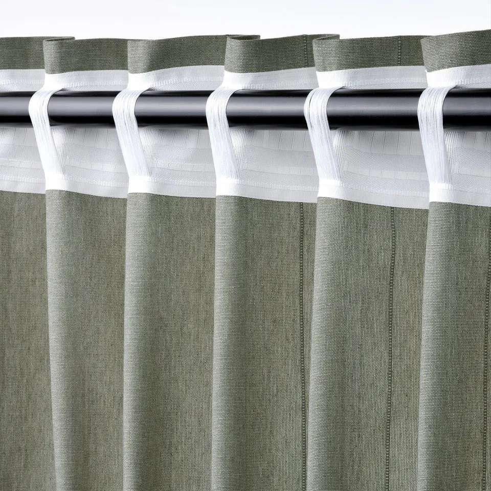Curtain header with hook tabs, ready for rod suspension, showing textured light grey-green fabric.