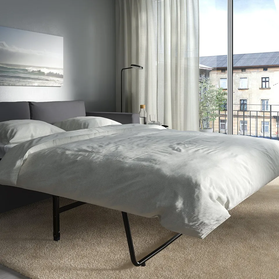 Modern bedroom with VIMLE sofa-bed and urban view.