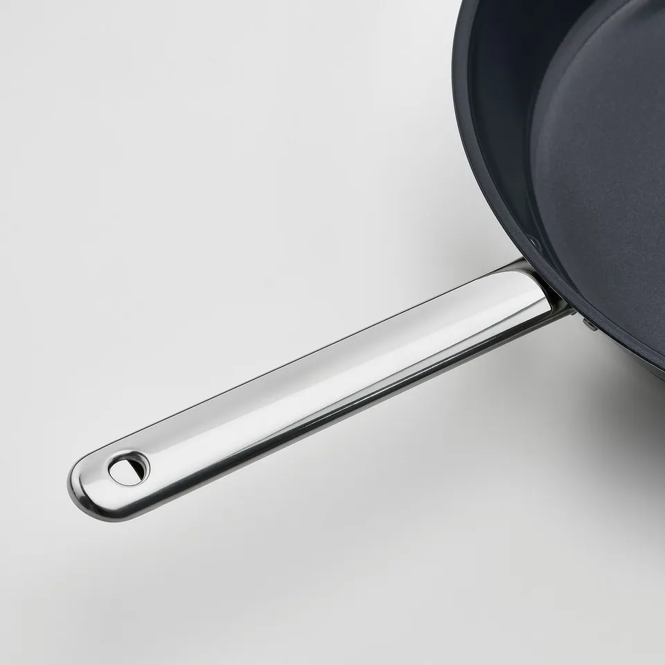 Stainless steel pan handle shown, quality finish, attached to dark pan.