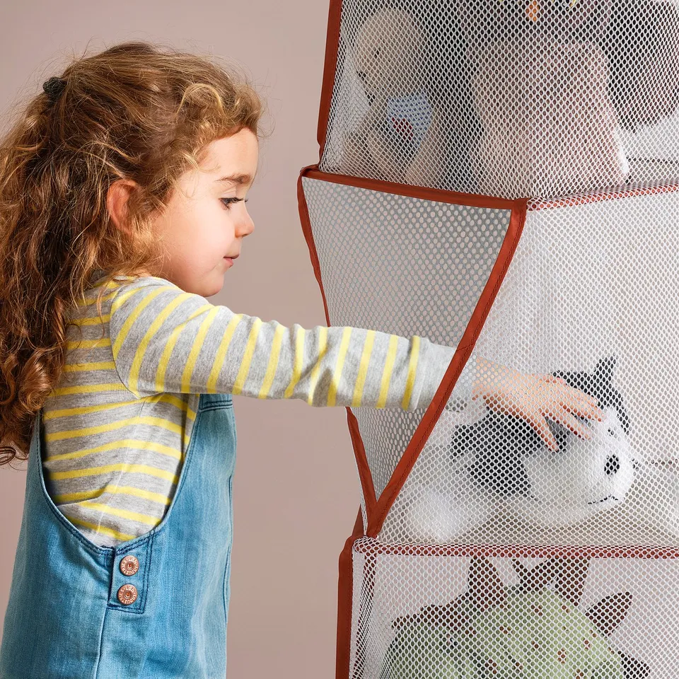 Child reaching into mesh toy organiser with 5 compartments. The organiser is lightweight and foldable, designed for easy storage and cleaning.