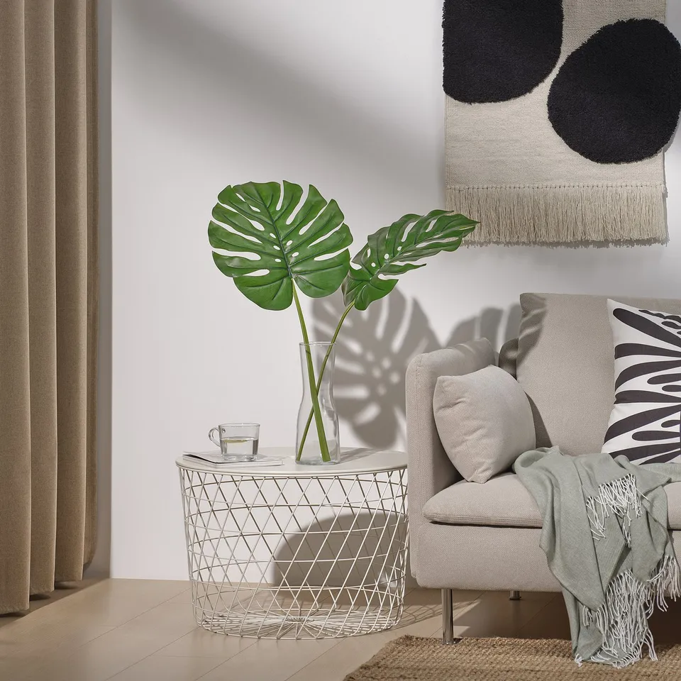 Modern living room with leaf in basket, cosy chair, and wall decor.