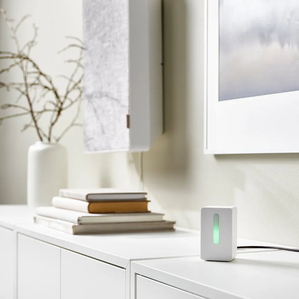 White FÖRNUFTIG air purifier on shelf with books and vase.