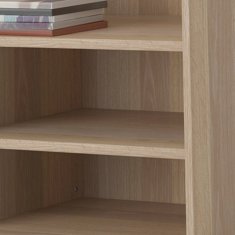 Wooden bookshelf with adjustable shelves, one shelf holding books.