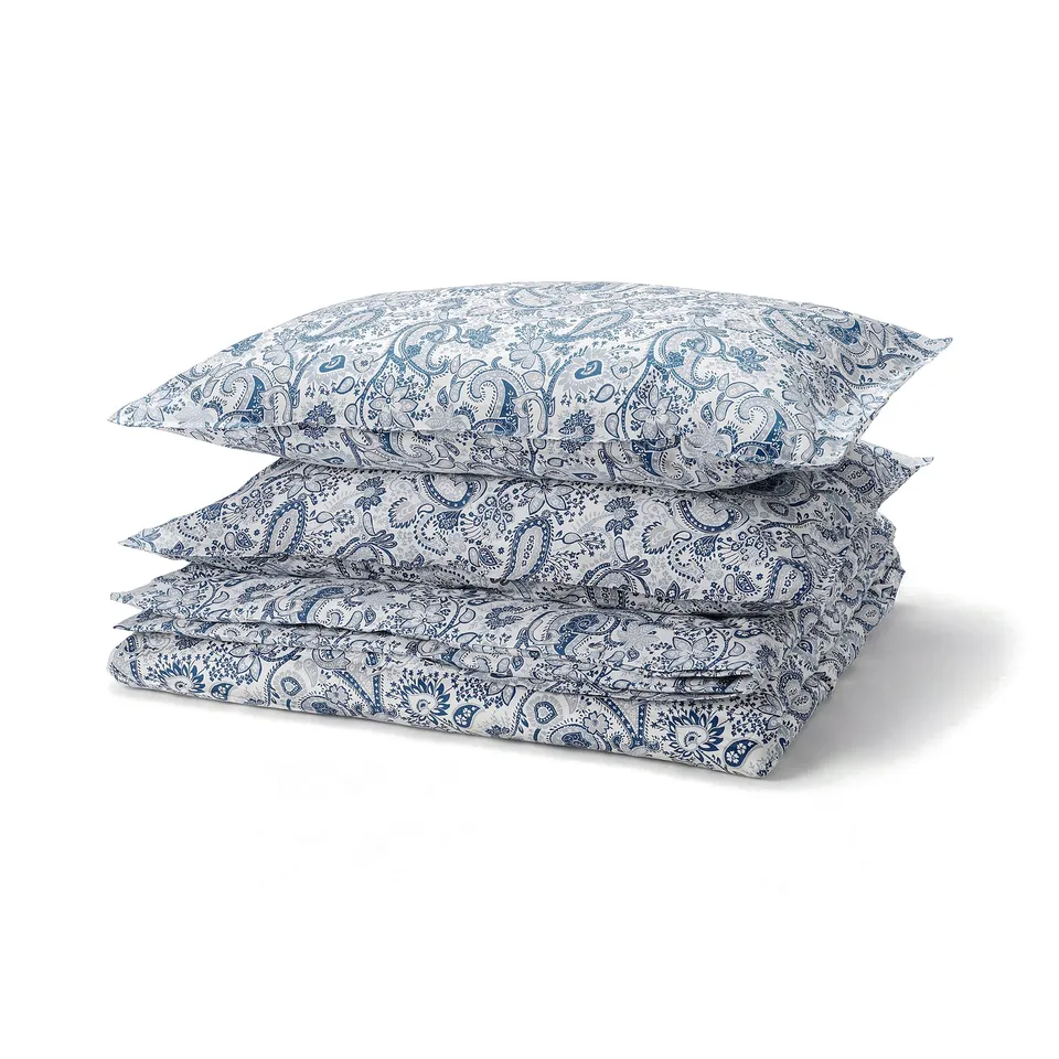 A stack of blue and white paisley-patterned RODGERSIA bedding in a cotton-viscose blend, featuring a soft, cool design.