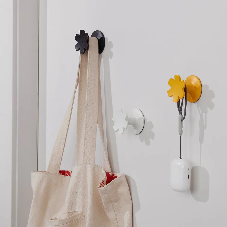 Three snowflake-shaped hooks on a wall, holding a bag, earphones, and a small electronic device.